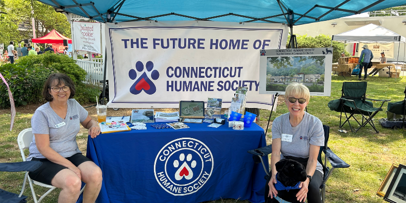 two people sitting at table in front of banner