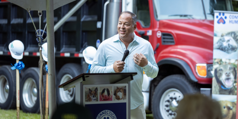 man speaking in front of large truck